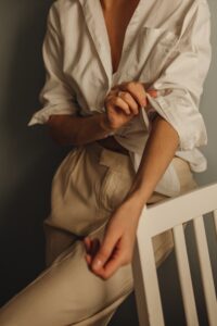 unrecognizable-woman-rolling-up-sleeves-of-white-blouse